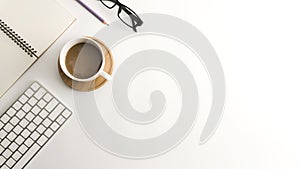 White office desk table with blank notebook, computer, supplies and coffee cup.