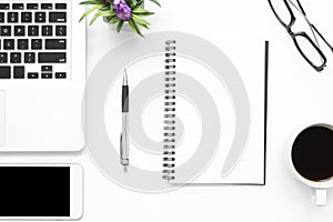 White office desk table with blank notebook, laptop computer, smartphone and supplies. Top view, flat lay