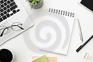 White office desk table with blank notebook and supplies. Top view, flat lay