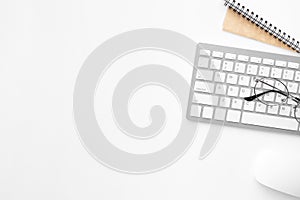 White office desk table with computer mouse, keyboard and supplies. Top view with copy space, flat lay