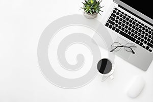 White office desk table with laptop computer, cup of coffee and supplies. Top view with copy space, flat lay