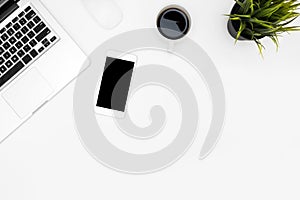 White office desk table with laptop computer, smartphone, cup of coffee and supplies. Top view with copy space, flat lay