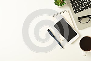 White office desk table with laptop, and smartphone and pen with coffee cup