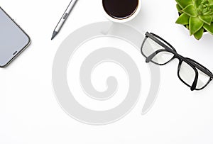 White office desk table with smartphone, glasses, coffee and plant.