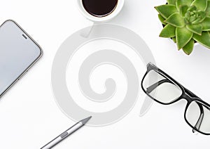 White office desk table with smartphone, glasses and other office supplies.