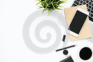 White office desk table with smartphone, laptop computer and supplies. Top view with copy space, flat lay