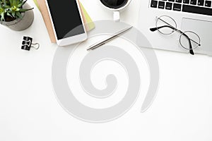 White office desk table with smartphone, laptop computer and supplies. Top view with copy space, flat lay