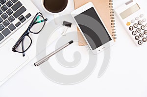 White office desk table, workspace office with laptop, smartphone black screen, coffee cup,pen,calculator, glasses, Top view with