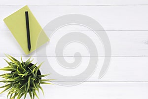 White office desk wooden table background with mock up notebooks and pencil and plant.