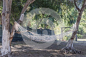 A white old hammock on a children's playground between the trees in the courtyard in summer