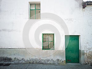 An white old house facade with green door and two little windows