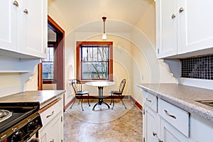 White old kitchen with small dining table.