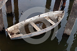 White old leaky boat half in the water on the river