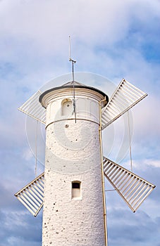 White old lighthouse windmill against a cloudy blue sky in Swinoujscie on the Baltic Sea in Poland in summer