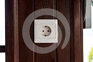 White old plastic power socket on a wooden wall outside. Bali.