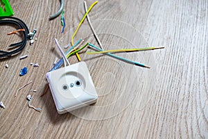 White old socket and multi-colored wires lie on the floor after repair. Electronics Repair Service. Concept of Electronics