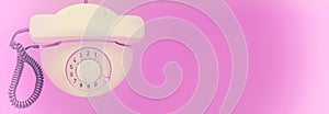 White old telephone with rotary dial on purple background. Faded effect. Flat lay. Top view. Banner