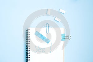 White open notebook with blue elements and gum on a light blue background