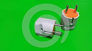 White and orance electric plug on green isolated photo