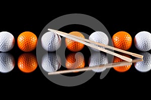 White and orange golf balls with bamboo chopsticks
