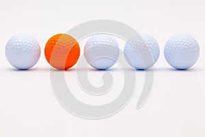 White and orange golf balls on the white desk