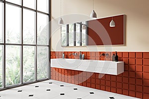 White and orange tiled bathroom corner with double sink and window