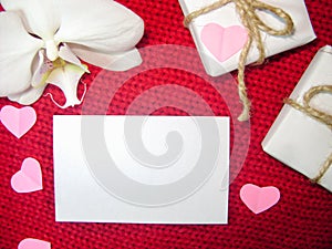 White orchid and gift box on a red background, Valentines Day background. Small paper hearts.