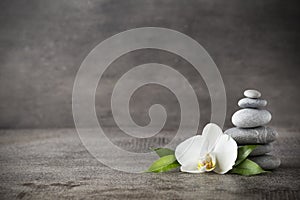 White orchid and spa stones on the grey background.