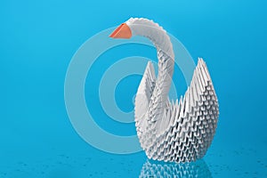 White origami swan made of paper with a red beak on a blue background