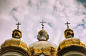 White Orthodox Church with big golden domes on a cloudy day