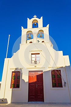 White Orthodox church building and bell tower in Oia Santorini Greece