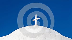 White orthodox greek church with cross on clear blue sky background. Summer vacation destination