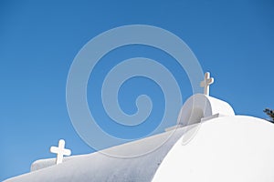 White orthodox greek church with cross on clear blue sky background. Summer vacation destination