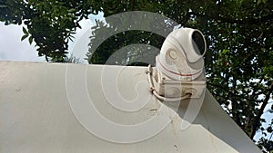 white outdoor cctv and the cable is attached to the corner of the fence wall