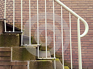 White outdoor metal stair railing with brick
