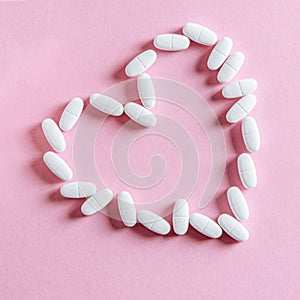 White oval heart-shaped tablets lie on a pink background
