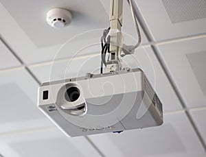 White overhead multimedia projector hanging on the ceiling