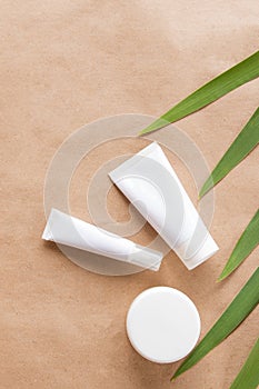 White packaging for cosmetics and green leaves on a natural paper background. Brand layout, self-care and sustainable lifestyle photo