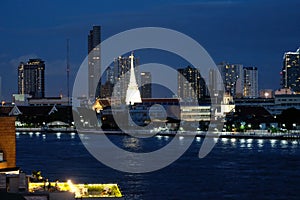 White pagoda amid surround buildings by a river in night light