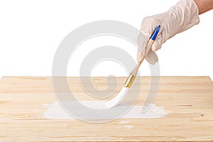 White paint with a brush painting a wooden background with texture