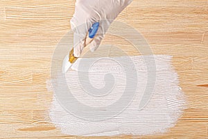 White paint with a brush painting a wooden background with texture