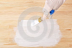 White paint with a brush painting a wooden background with texture