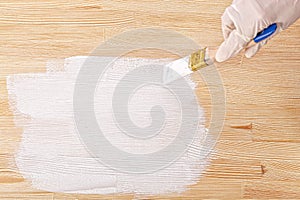 white paint with a brush painting a wooden background with texture