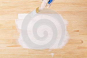 white paint with a brush painting a wooden background with texture