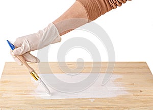 White paint with a brush painting a wooden background with texture