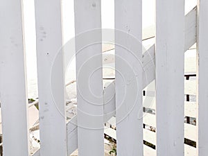 White paint wooden plakes fence in soft sunlight. Wood construction near sea. Beach bar wooden fence