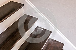 white painted and dark stained wood stairs in a new construction home with sheetrock dust from hole in the wall above