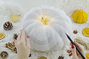 White painted pumpkin mockup for atr, hand lettering. Woman with a calligraphic brush pen draws on a white pumpkin. Top