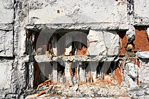 White painted wall with broken red bricks