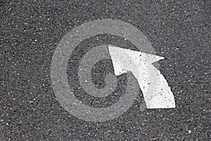 White painting in turn left direction arrow symbol on black asphalt road
